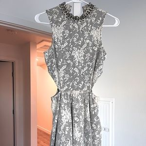 Black and white brocade mini dress with bronze studs and side cutouts.